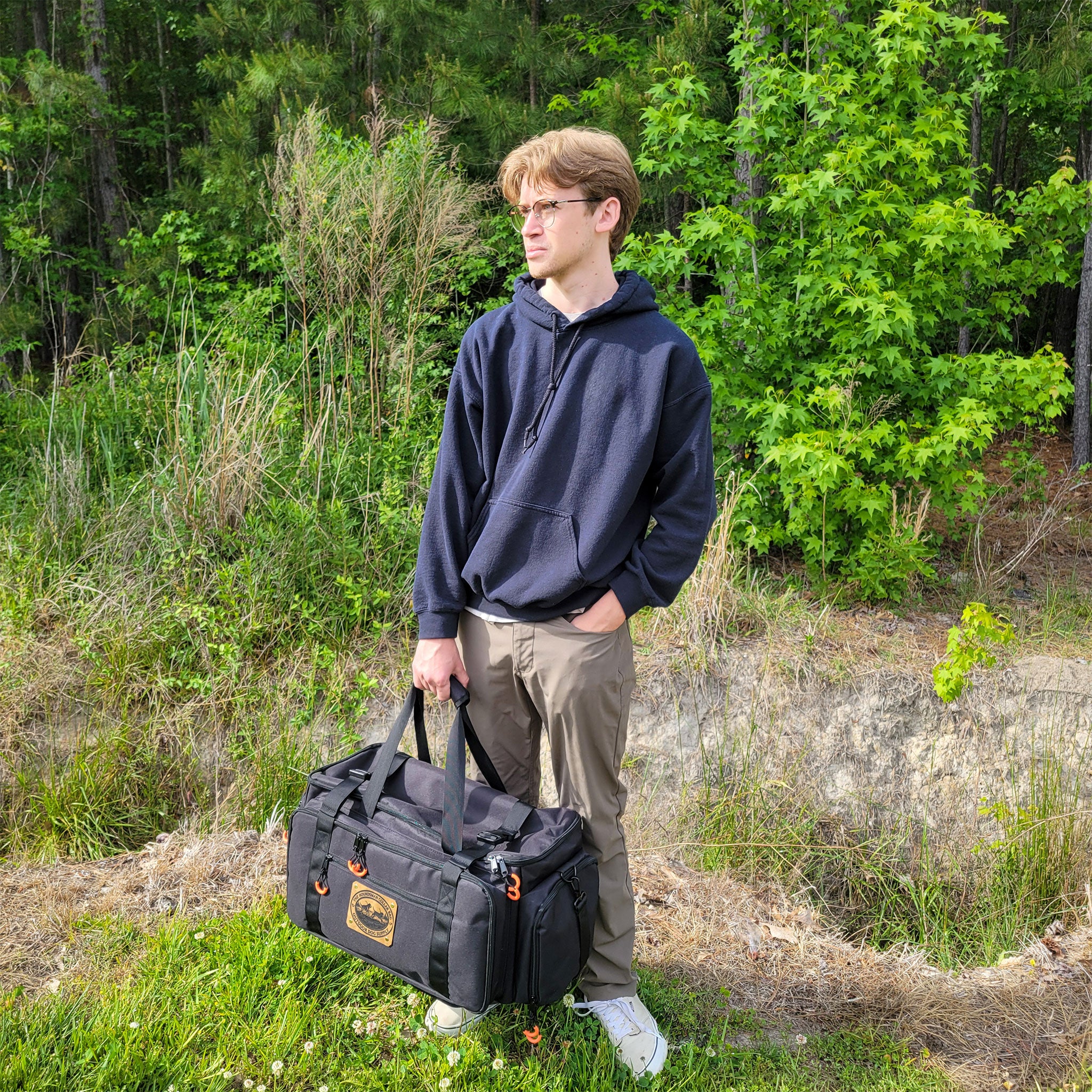 guy holding the houndsmen charging and travel bag by handles