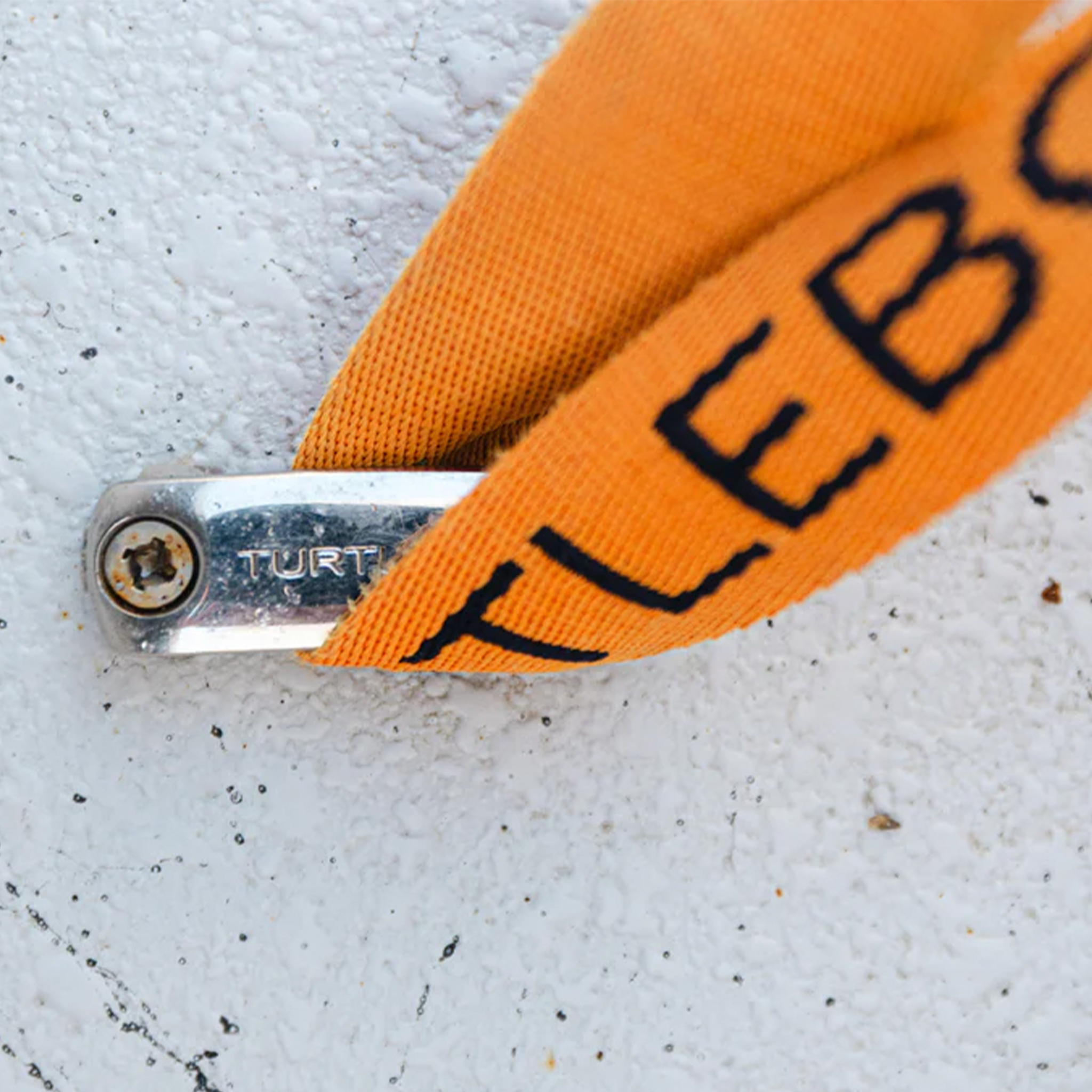 close up of turtlebox strap being held down with Turtlebox Stainless Anchor Kit